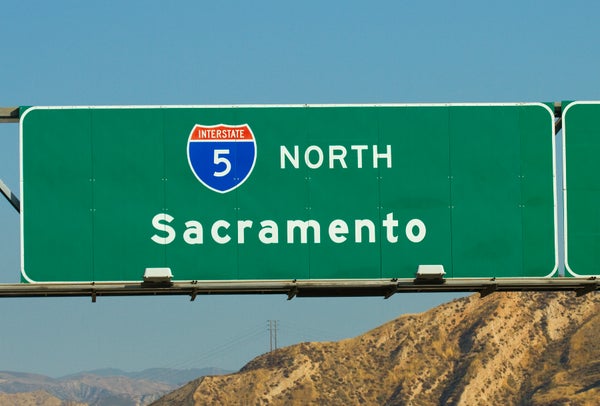 A green highway sign reading &quot;Interstate 5 North Sacramento&quot; with mountains in the background